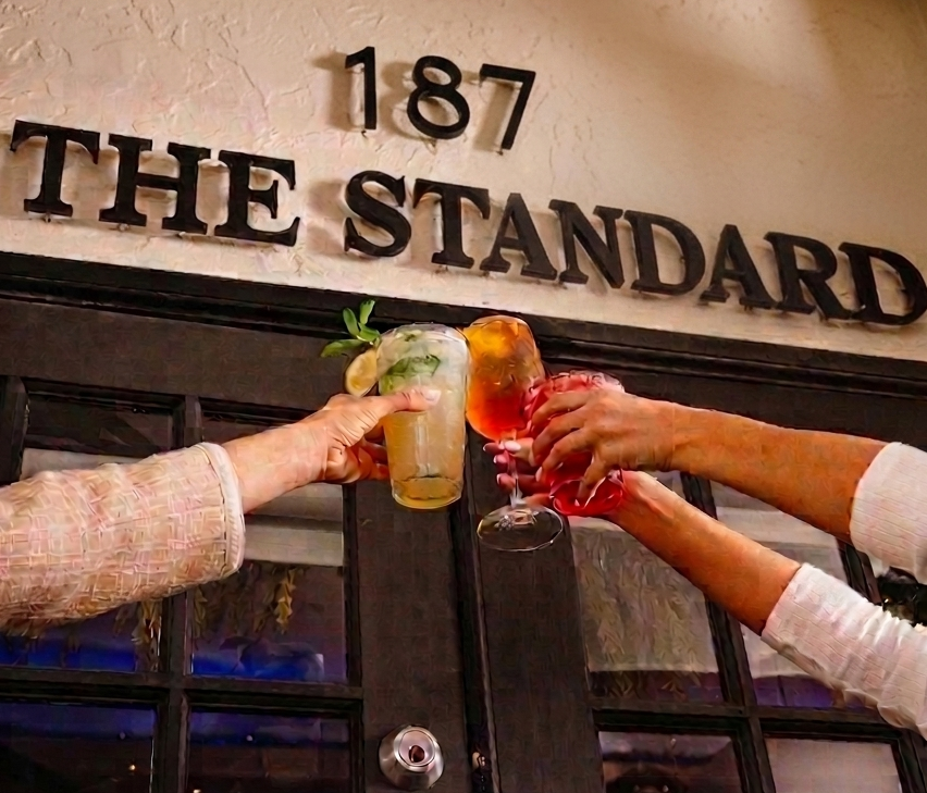 Guests raising a toast beneath The Standard's sign